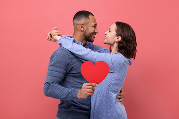 Fototapeta na wymiar Lovely couple with paper heart on red background. Valentine's day celebration