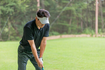 ゴルフ練習場・打ちっぱなし・ゴルフセンターでスイングの練習するゴルフ選手・ゴルファーの男性
