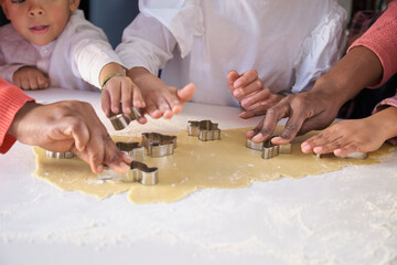 African family hands cutting cookie shapes in a cookie dough in the kitchen. Horizontal extended family.