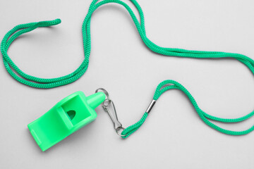 One green whistle with cord on light grey background, top view