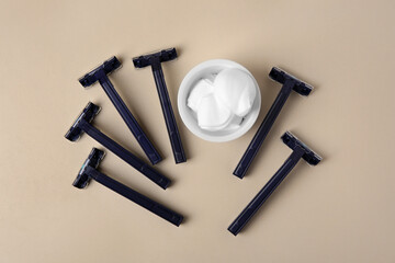 Razors and shaving foam on beige background, flat lay