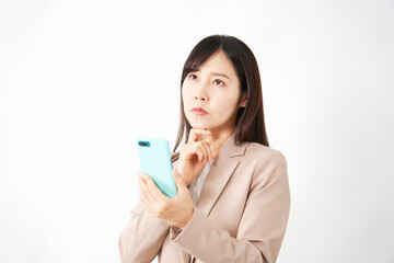 スマートフォンを持って考えるミドルエイジのビジネスウーマン　白背景