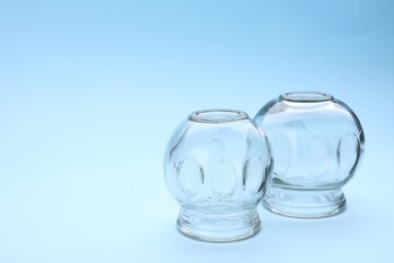 Glass cups on light blue background, space for text. Cupping therapy