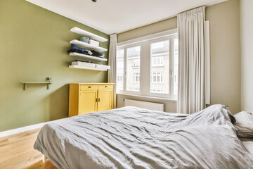 a bedroom with green walls and white trim on the window sies, in front of a yellow chest cabinet