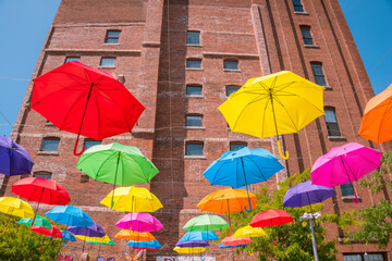 Fototapeta na wymiar Beautiful colorful umbrellas against a deep blue sky and brick building.
