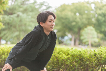 運動前に屈伸・ストレッチ・準備体操・ウォーミングアップする若いアジア人男性
