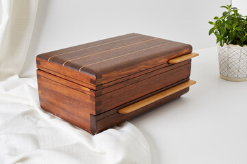 Wooden jewelry box. Product photograph with white cloth and a houseplant.