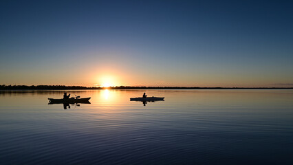 Two kayakers on calm water of Coot Bay in Everglades National Park, Florida at sunset.
