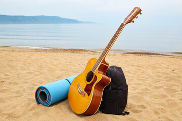 Guitar, backpack and other things for outdoor recreation, by the sea, hiking. The concept of traveling through wild places, solitude with nature.