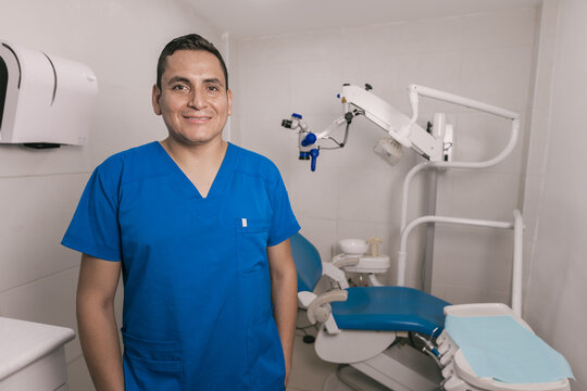Portrait of latin dentist standing by dental equipment in clinic