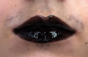 close up of a woman's lips with a mustache with black lip gloss on 