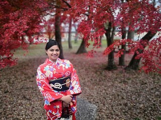 Woman dressed in a kimono with a Japanese maple tree in autumn background