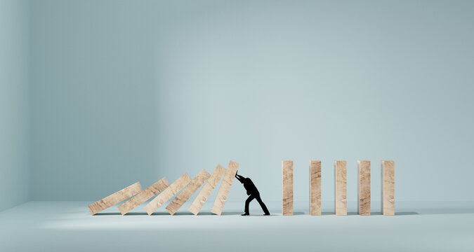 Silhouette of a man in panic against collapsing wooden dominos. Business crisis and failure concept in wide view.