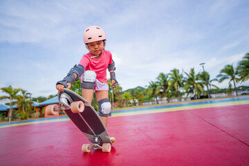 asian child skater or kid girl play skateboard or ride surf skate and ollie jumping fun or lifting...