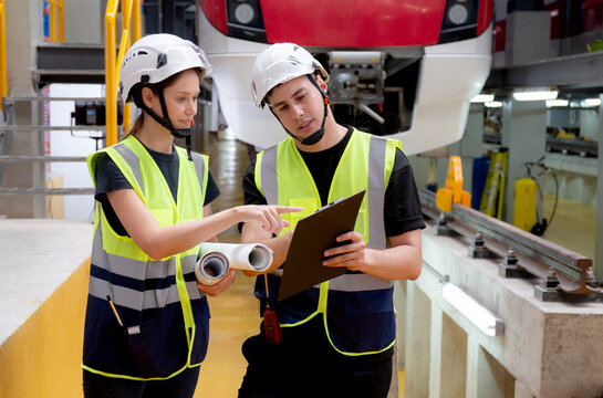 Young caucasian engineer man and woman checking electric train for planning maintenance looking document on clipboard in station, transport and infrastructure, inspector check service transport.