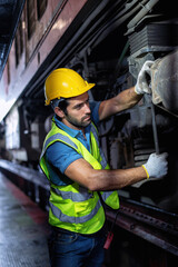 Mechanics service engineer working underneath train car maintenance transmittal system in the garage