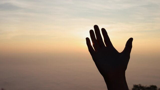 silhouette of a woman raising her hands while the sun is rising for worshiping God. Struggle. Victory. Praise to God spiritually and religiously. Success on the top of the mountain.4K slow motion.