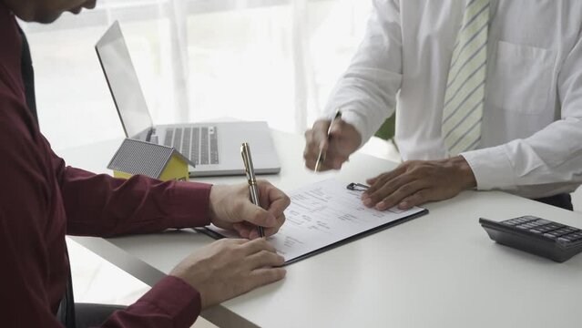 Homebuyers meet and negotiate with a real estate agent about renting or buying a home and the terms of the home purchase agreement and ask the client to sign paperwork to complete the sale.