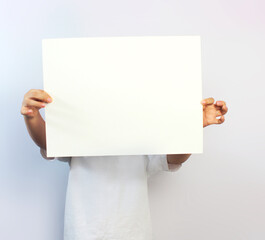 hands of a child holding in front of him a blank paper on a white background