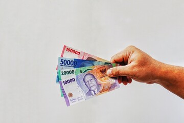 Man's hand holding rupiah money isolates on white background. 