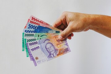 Man's hand holding rupiah money isolates on white background. 