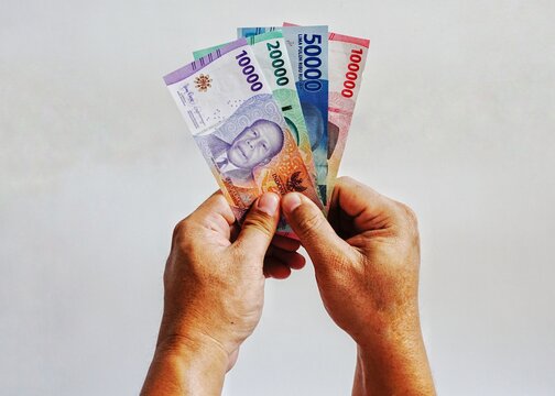 Man's hand holding rupiah money isolates on white background. 