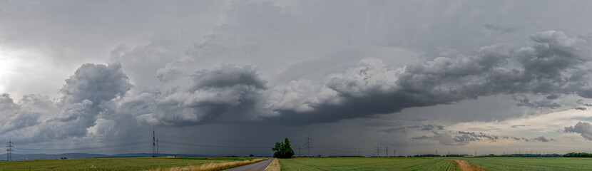 Obraz na płótnie Canvas Panoramaansicht eines über das Land ziehenden schweren Unwetters mit grauem, bedeckten Himmel und Feldern im Vordergrund