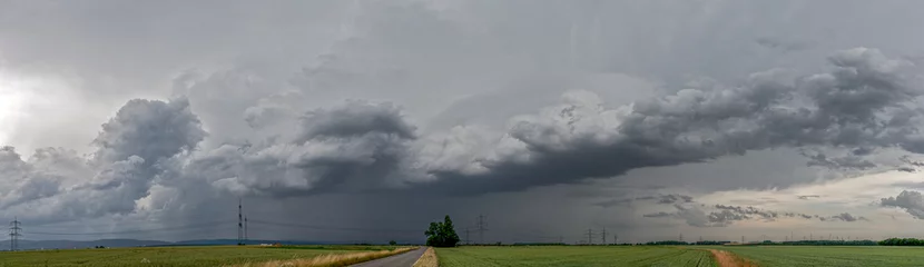 Fotobehang Panoramaansicht eines über das Land ziehenden schweren Unwetters mit grauem, bedeckten Himmel und Feldern im Vordergrund © Frank Wagner
