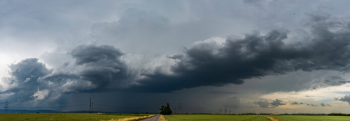Panoramaansicht eines über das Land ziehenden schweren Unwetters mit grauem, bedeckten Himmel und Feldern im Vordergrund