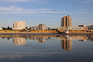 Skyline von Häusern am Strand von Cuxhaven Duhnen spiegelt sich im Wasser der Nordsee am Abend