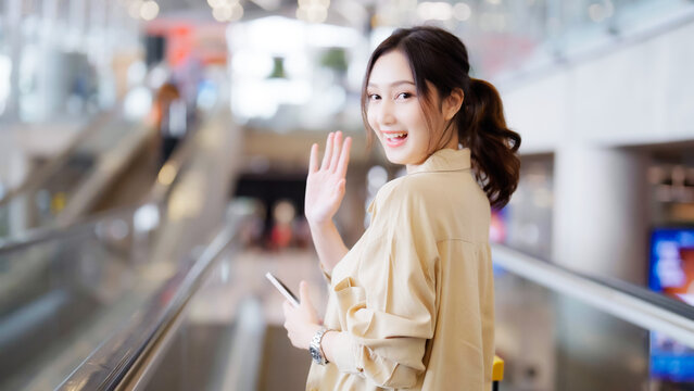 Young asian woman passenger in airport terminal or modern train station. Asia woman commuter travels with luggage on escalator