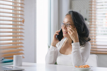 The Senior businesswoman adviser is analyzing and discussing the financial report situation on smartphone in her home office, financial, accounting, and investment advisor concepts.