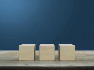 Three wood block cubes on wooden table over blue wall