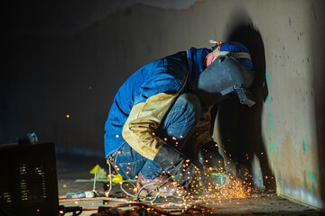 Male worker  grinding on steel plate with flash of sparks close up wear protective gloves oil inside