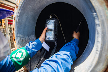 Worker female hand holding gas detector inspection safety gas testing at front manhole tank...