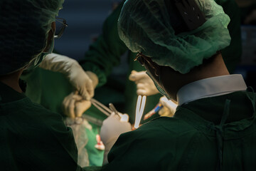 Medical team of surgeons in hospital working surgical intervention.Surgery operating room with electrocautery equipment for breast cosmetic.Surgeon gloved hands hold the instrument