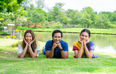 Fototapeta premium young diversity genders friends,man,woman and woman transgender enjoy leisure time in the summer park,lying on grasses take pleasure in nature,concept of people lifestyle,health benefit in nature