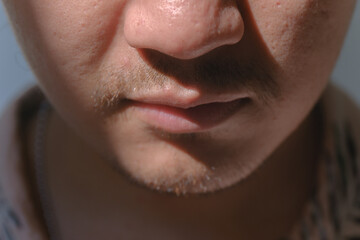 Close-up and soft focus shot of a man's partial face with a little mustache and beard. Bokeh or blurred background.