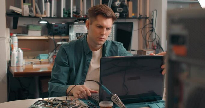 Unhappy sad irritated blonde handsome man in casual shirt have problem with broken laptop Electronics repair IT concept, specialist cannot solve computer problem Slow motion