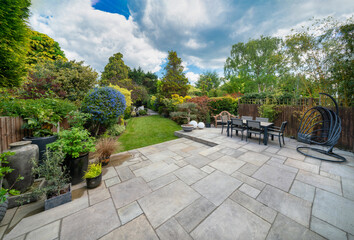 Beautiful summer garden in England, UK with lawn and large indian sandstone patio. - obrazy, fototapety, plakaty
