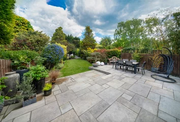 Fotobehang Beautiful summer garden in England, UK with lawn and large indian sandstone patio. © Wormsmeat