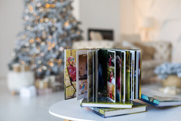Naklejka na ściany i meble Photo book album under the Christmas tree surrounded by Christmas gifts
