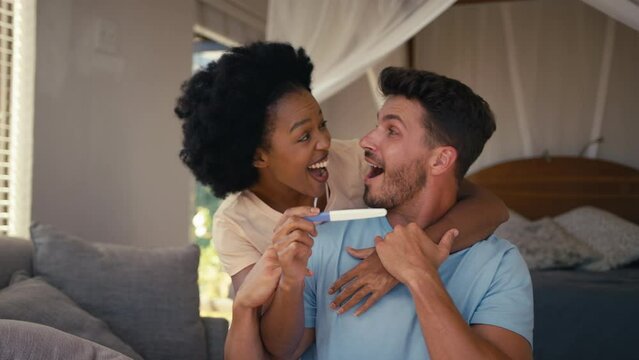 Excited couple in bedroom at home celebrating positive pregnancy test result - shot in slow motion