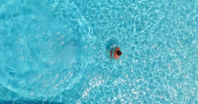 Aerial view as a man dives into the pool and swims, slow motion