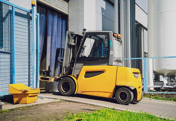 Forklift loader near big industrial storage warehouse.