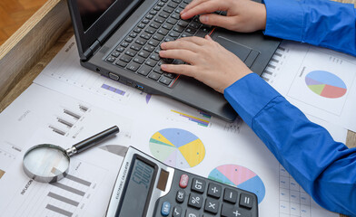 Praca w finansach, biurko z komputerem otoczonym papierami z wykresami i danymi