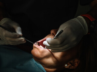 Dentist opens the mouth of his patient and begins to revise the interior helped by his instruments.