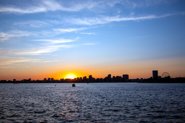 the silhouette of the city by the water at sunset
