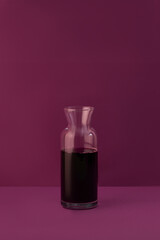 Decanter with red wine on purple background
