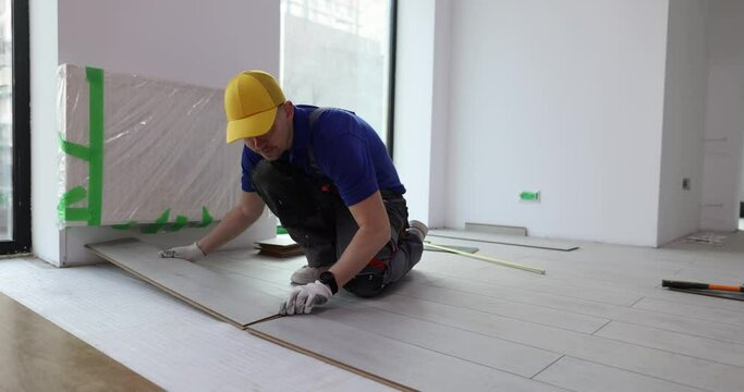 Work of master on installation of floating floors laying laminate on floor. Construction services and installation of new floor